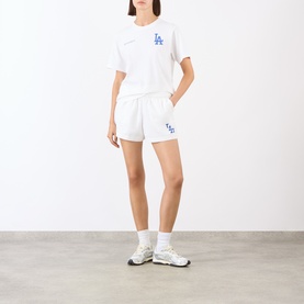 Model wearing Sporty and Rich White Team Blue cotton shorts with LA Dodgers graphic, styled with matching white tee and trainers.