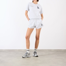 Model wearing Sporty and Rich Heather Gray Navy shorts with matching tee, white socks and grey trainers.