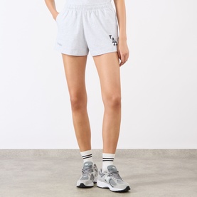 Model wearing Sporty and Rich Heather Gray Navy shorts with LA logo, styled with white socks and grey trainers.