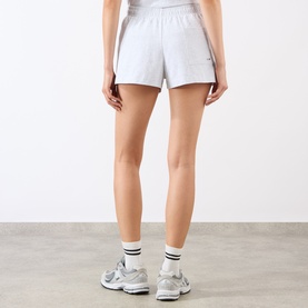 Model wearing Sporty and Rich Heather Gray Navy cotton shorts, rear view, styled with white socks and grey trainers
