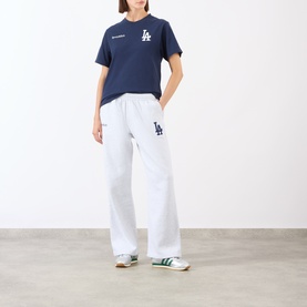 Model wearing Sporty and Rich Heather Gray Navy sweat bottoms with LA logo, styled with navy tee and green trainers.