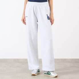 Model wearing Sporty and Rich Heather Gray Navy sweat pants with LA logo, wide-leg fit, styled with white and green trainers.
