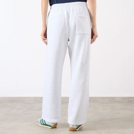 Model wearing Sporty and Rich Heather Gray sweat pants, wide-leg fit, rear view, styled with green and white trainers.