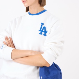 Model wearing Sporty and Rich White Team Blue cotton sweat top with blue LA Dodgers logo, styled with matching blue cap.