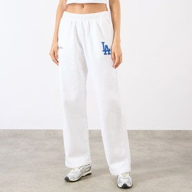 Model wearing Sporty and Rich White Team Blue cotton sweat bottoms with blue LA Dodgers logo, styled with white trainers.
