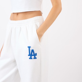 Model wearing Sporty and Rich White Team Blue sweat bottoms with blue LA Dodgers logo embroidery on hip, paired with white crop top.