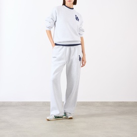 Model wearing Sporty and Rich Heather Gray Navy sweatpants with matching crew neck sweatshirt, styled with green trainers.