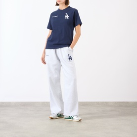 Model wearing Sporty and Rich Dark Navy White LA Dodgers cotton T-shirt, styled with white wide-leg sweatpants and green trainers.