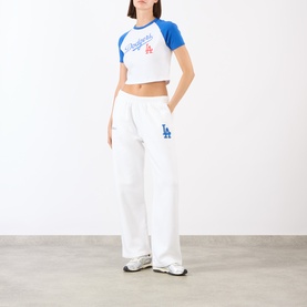 Model wearing Sporty and Rich white and blue raglan crop top with LA Dodgers print, styled with matching white wide-leg joggers.