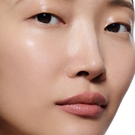 Model wearing Victoria Beckham Lip Definer in a soft mauve-nude shade, shown in a close-up beauty shot with luminous skin.