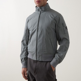 Model wearing Belstaff Atlantic Grey casual jacket with ribbed cuffs, zip front, funnel collar, and sleeve lens pocket, styled with dark trousers