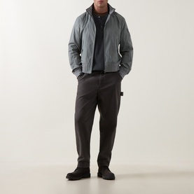 Model wearing Belstaff Atlantic Grey casual jacket with dark trousers and black shoes, hands in pockets.