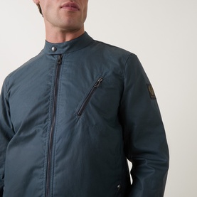 Model wearing Belstaff casual jacket in petrol blue, featuring zip chest pocket, stand collar, and front zip fastening.