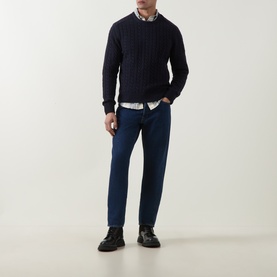 Model wearing Belstaff Dark Ink cable-knit crew neck jumper, styled with blue jeans, white shirt and black leather shoes.