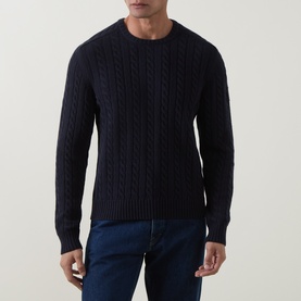 Model wearing Belstaff Dark Ink cable-knit crew neck jumper in cotton-wool blend, styled with dark blue jeans.