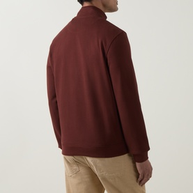 Model wearing Belstaff Half Zip sweatshirt in oxblood cotton, shown from rear. Styled with beige trousers.