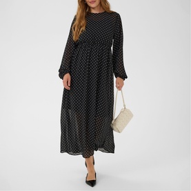 Model wearing Kaffe black with white dot maxi dress, long sleeves, styled with cream quilted mini bag and black heels