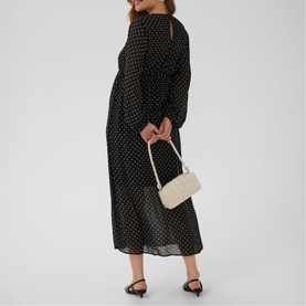 Model wearing Kaffe black with white dot midi dress, long sleeves, carrying cream mini bag, styled with black heeled mules