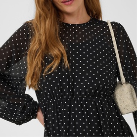 Model wearing Kaffe black and white dot dress with long sleeves, styled with a small cream crossbody bag.
