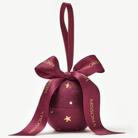 Missoma gold bracelet in burgundy star-embossed bauble gift box with satin bow, presented as Christmas ornament packaging
