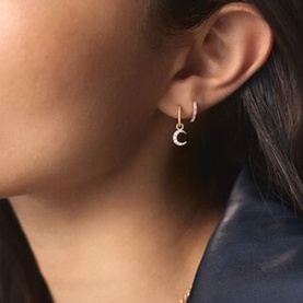 Model with Missoma Crescent Hoop Earrings in gold, featuring cubic zirconia crescent moon charm on a mini hoop with latch fastening.