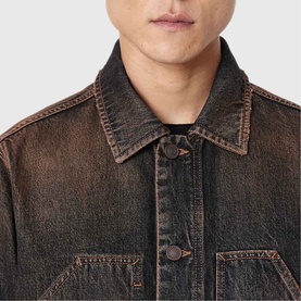 Model wearing All Saints washed brown denim jacket, close-up detail of collar and button placket with contrast stitching.