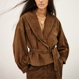 Model wearing Bash Manon Belted Suede Jacket in brown with large cowl collar, belted waist and rounded sleeves, styled with matching skirt and gold