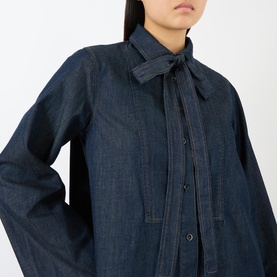 Model wearing FRAME DENIM Rinse denim dress with tie neck collar and button-front detail, in dark indigo wash cotton-lyocell blend.