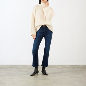 Model wearing FRAME DENIM ecru wool knit jumper with mock neck, styled with dark indigo cropped jeans and black heeled ankle boots