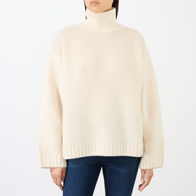 Model wearing FRAME DENIM ecru wool turtleneck sweater with ribbed texture and relaxed fit, styled with blue jeans.