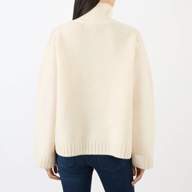 Model wearing FRAME DENIM ecru wool turtleneck knit sweater, rear view, with relaxed fit and ribbed hem, styled with blue jeans