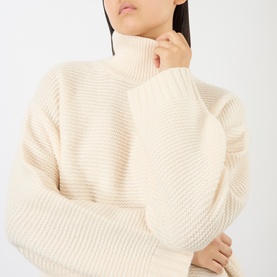Model wearing FRAME DENIM ecru wool turtleneck knit sweater with chunky ribbed texture and relaxed balloon sleeves