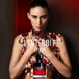Model with Givenchy L'Interdit Elixir Eau De Parfum bottle, wearing red jewelled bodypiece, deep red campaign backdrop