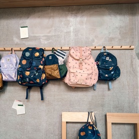 Liewood children's backpacks displayed on wall hooks in assorted colours including Cherry Heart Rosey pink with gold buckle clasp