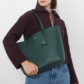 Model carrying Lauren Karly Reversible Faux-Leather Tote Bag in green with gold-tone hardware and dual shoulder straps, styled with a burgundy knit