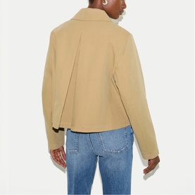 Model wearing Jigsaw beige jacket, back view, styled with light blue denim jeans.
