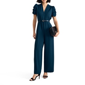 Model wearing Phase Eight blue wide-leg jumpsuit with puff sleeves, V-neck, and belt, styled with black heels and small clutch bag.