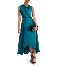 Model wearing Phase Eight blue sleeveless midi dress with cowl neck, hi-low hem, and belt detail, styled with black strappy heels and clutch bag