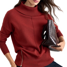 Model wearing Phase Eight orange funnel-neck knit sweater with zip hem detail, styled with a dark croc-effect clutch bag