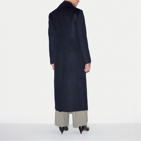 Model wearing Jigsaw navy wool long coat, rear view, styled with wide-leg trousers and black heeled mules