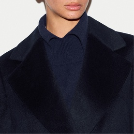 Model wearing Jigsaw navy coat with wide lapels, styled with a navy knit jumper underneath, close-up detail view