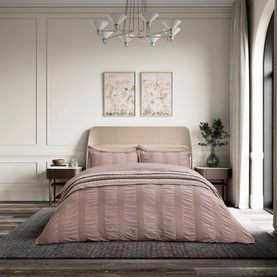 Bedeck Belfast pink duvet set styled on a double bed with matching pillowcases, featuring a ruched stripe texture, in an elegant bedroom setting.