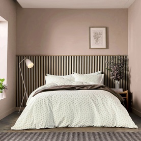 White ditsy floral print duvet cover set styled on a double bed in a neutral bedroom with wood-panelled headboard wall