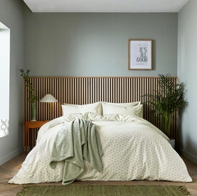 Helena Springfield Green Duvet Set styled on a double bed with matching pillowcases, shown in a sage-toned bedroom with plant d&eacute;cor.