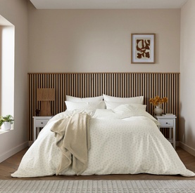Cream ditsy floral print duvet set styled on a double bed with coordinating pillowcases, in a neutral bedroom setting