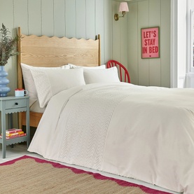 Cream duvet cover set with embroidered floral detail, styled on a double bed with matching pillowcases in a cosy bedroom setting.