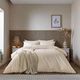 Cream duvet set styled on a double bed with matching pillowcases, in a neutral bedroom with wooden slatted headboard