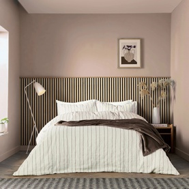 White and grey pinstripe duvet set styled on a double bed with a chocolate brown throw, in a soft pink bedroom setting.