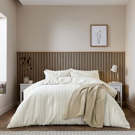 Cream striped duvet cover set styled on a double bed with matching pillowcases, in a neutral Scandi-inspired bedroom setting.