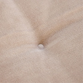 Close-up of a beige fabric cushion with a single central button detail, showing soft textured upholstery